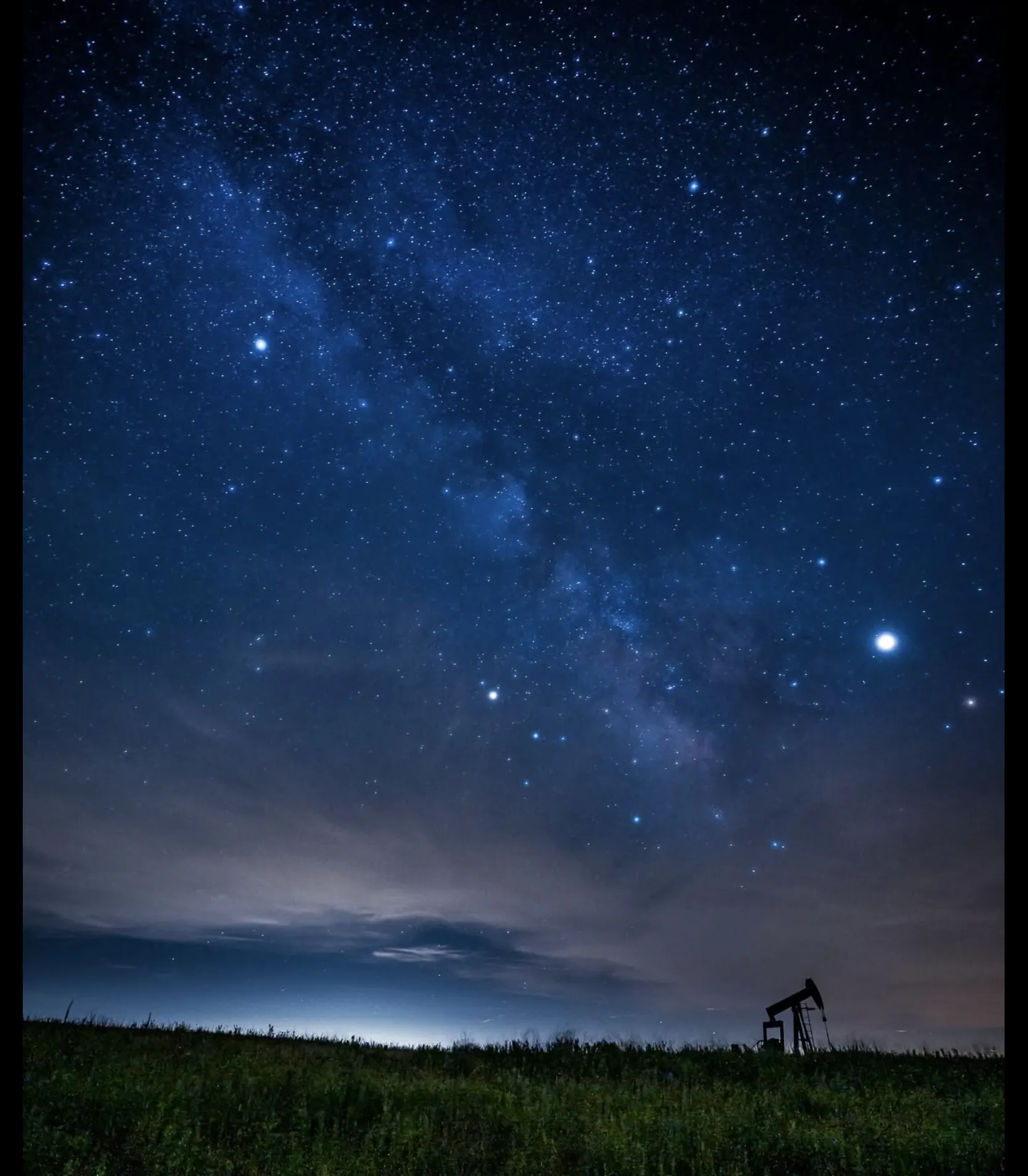 Open prairie and a pumpjack beneath the stars